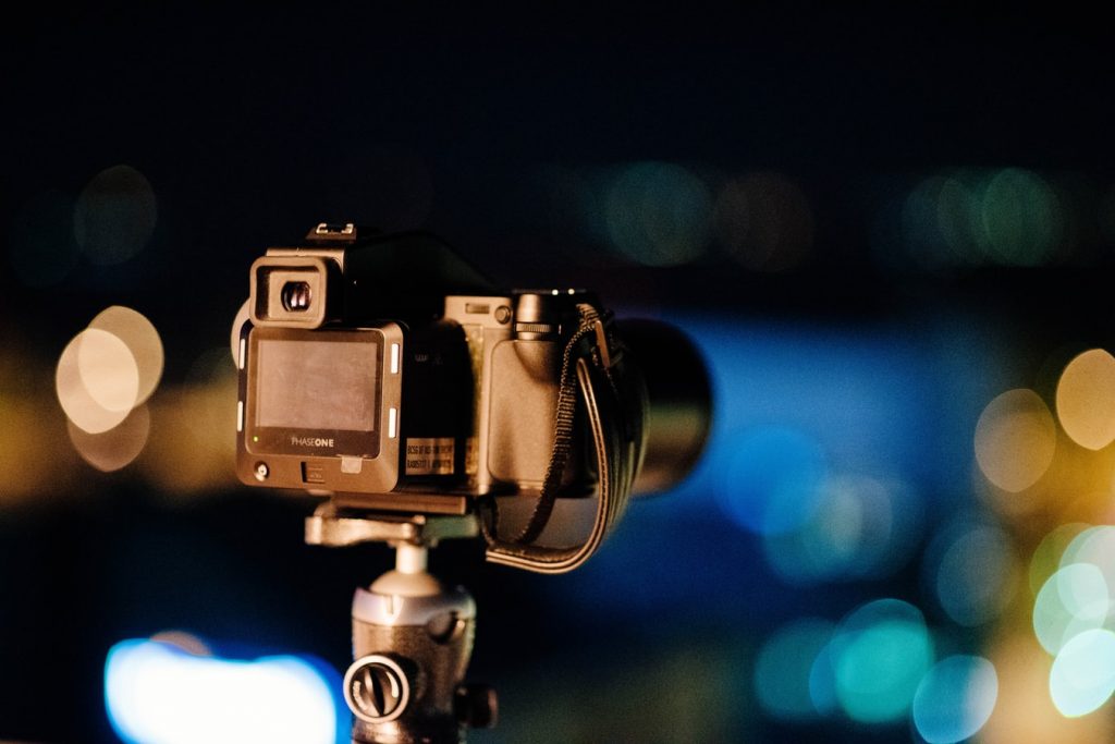 Caméra sur trépied avec des bokeh de lumière en arrière-plan, ambiance nuit